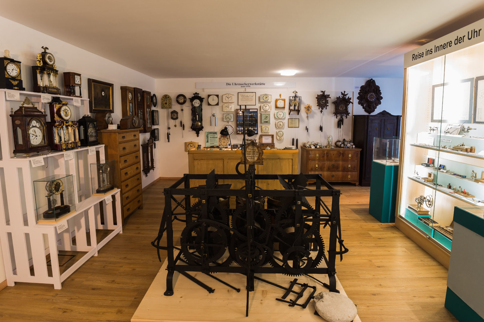 viele verschiedene Uhren an den Wänden des Uhrmacherhandwerkmuseums, in der Mitte steht ein großes, altes Uhrwerk