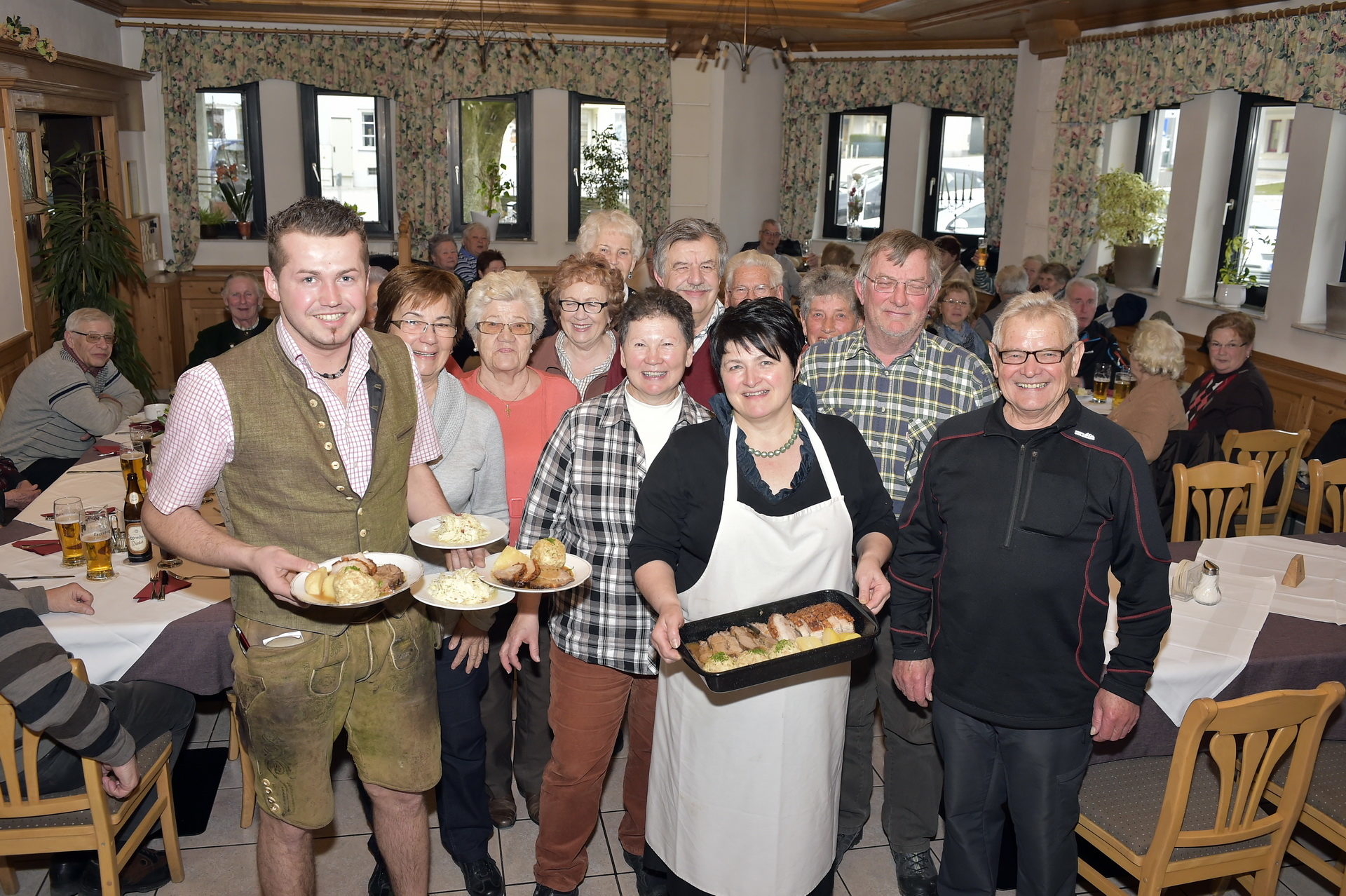 Bratl im Gasthof Pöll, viele Personen im Innenraum, im Vordergrund ein Bratl in da Rein