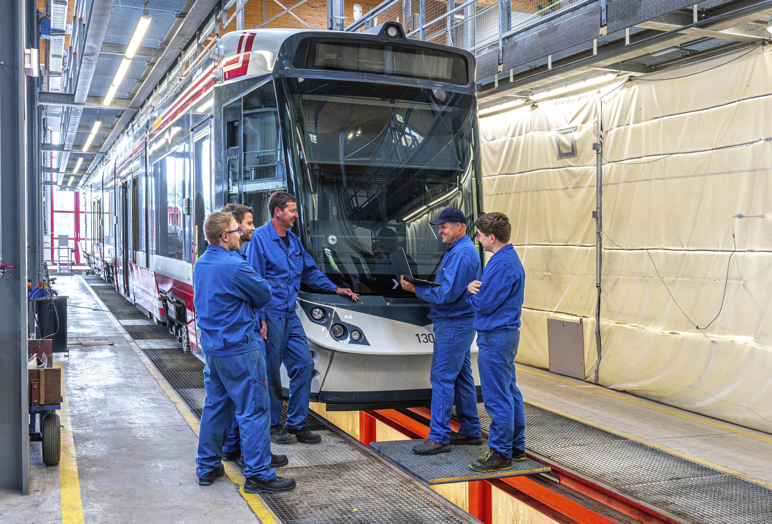 4 Mitarbeiter stehen neben der Bahn und begutachten diese