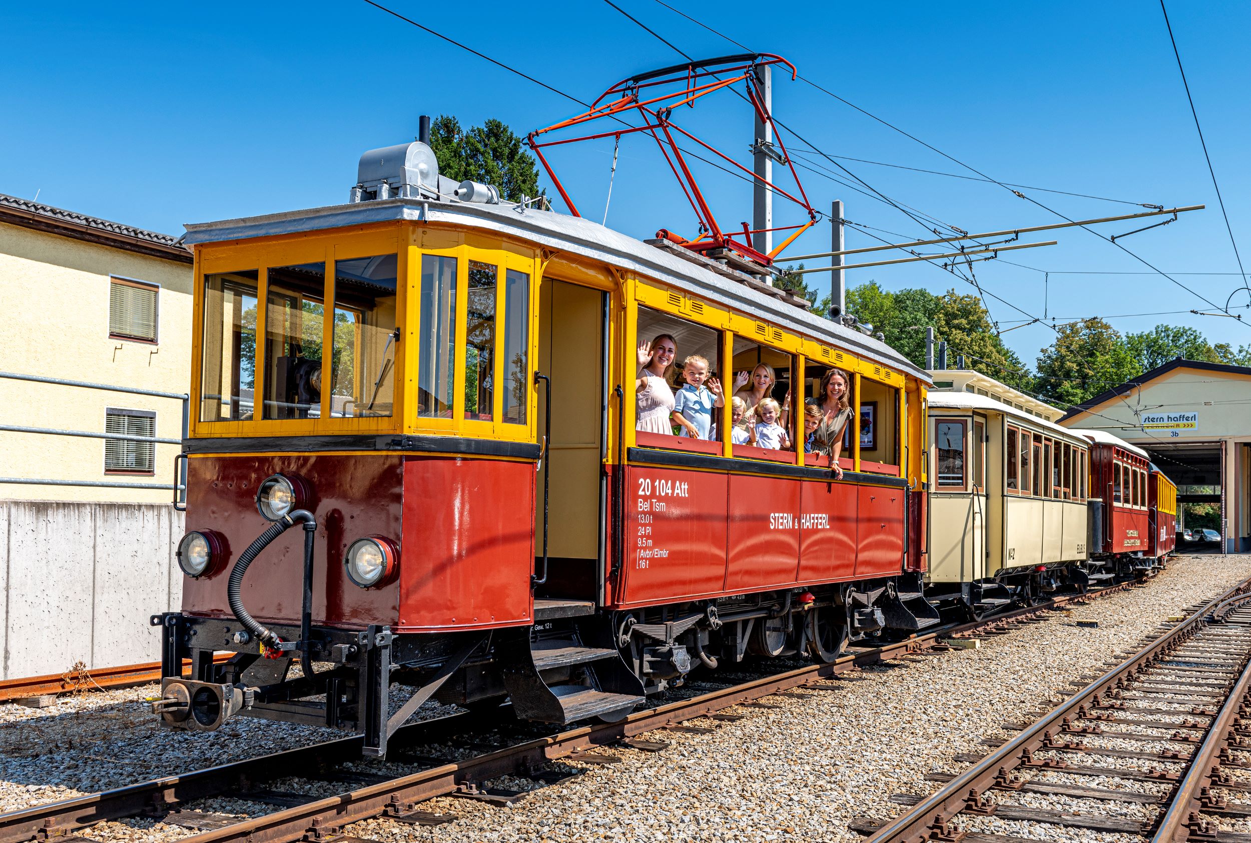 Familie lacht und winkt aus der Atterseebahn heraus