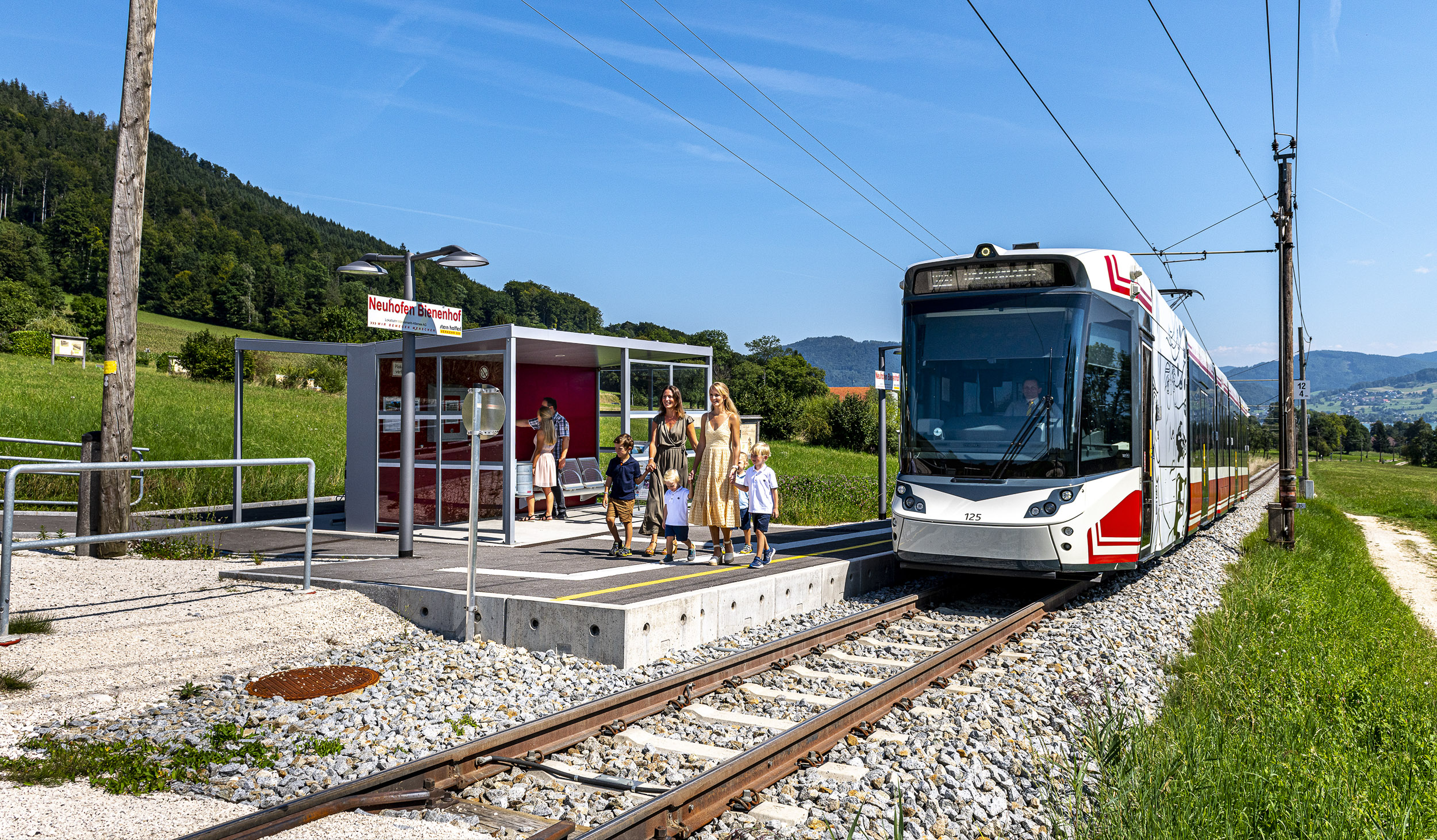 eine Familie steigt beim Bienenhof aus der Atterseebahn aus