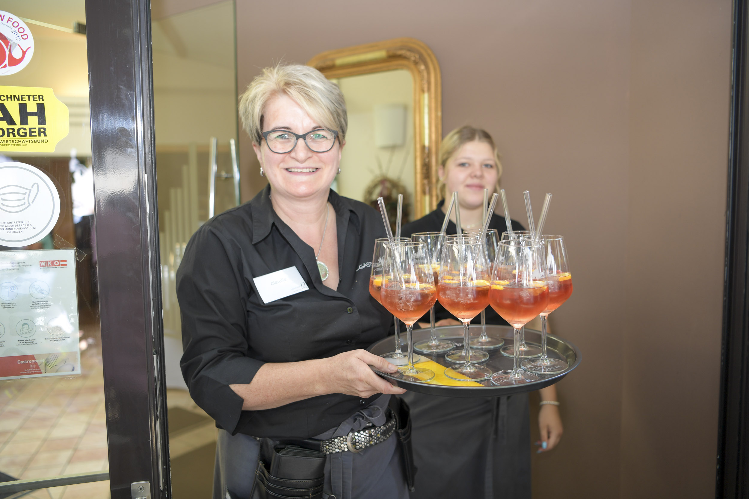 Lachende Kellnerin mit Aperitif am Tablett