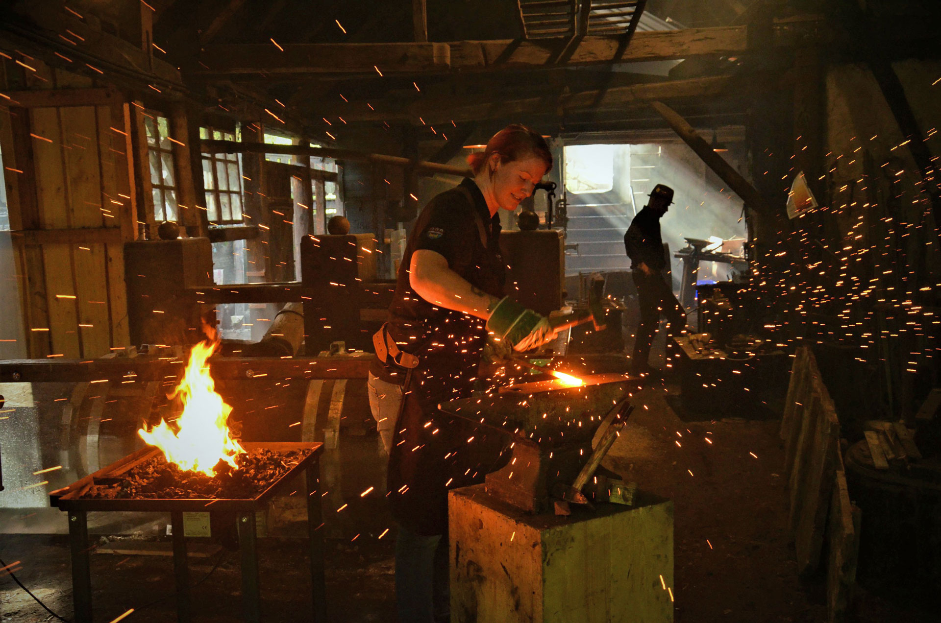 eine Frau beim Schmieden in der Hackenschmiede Bad Wimsbach, Funkenflug und Feuer