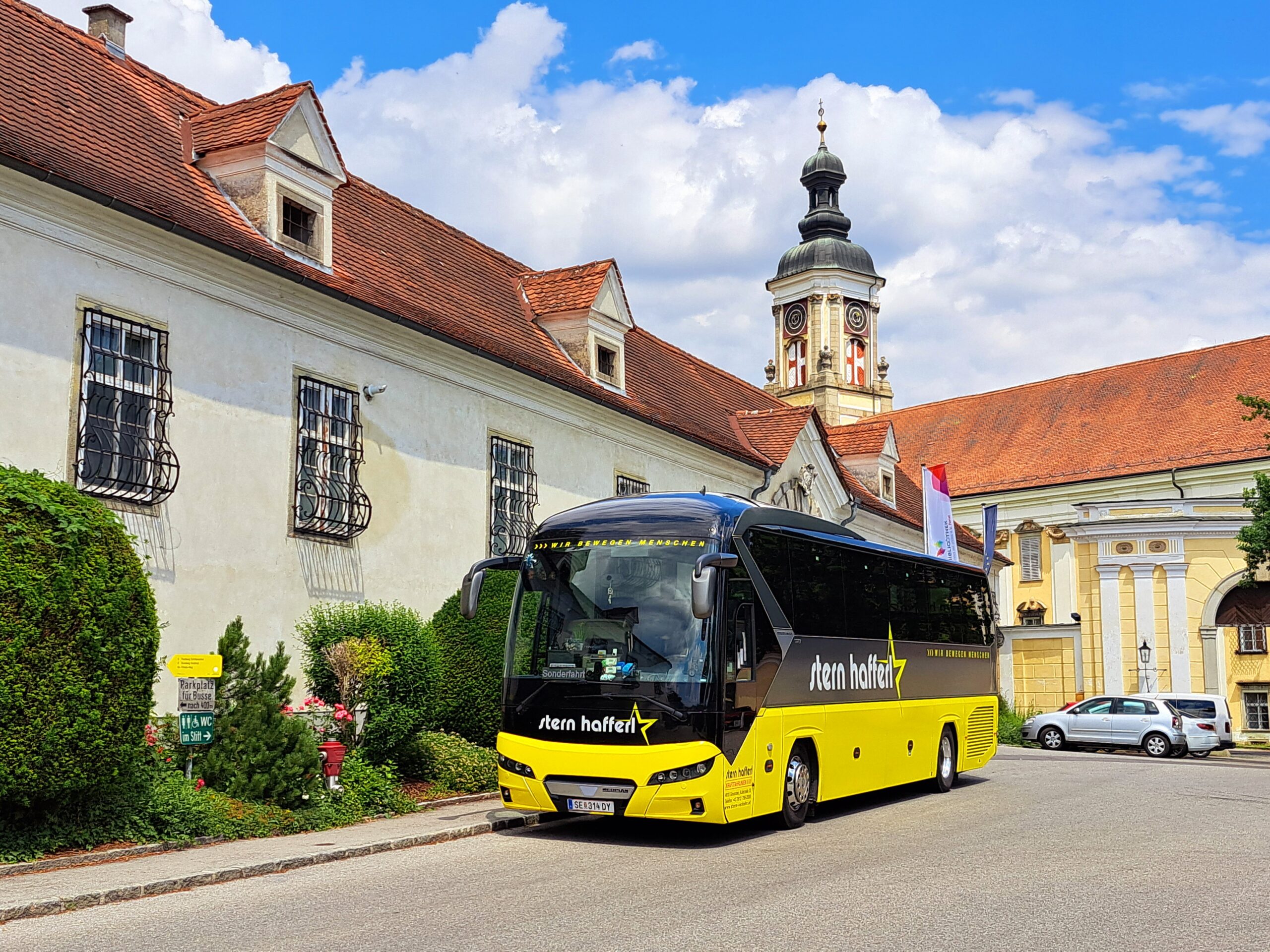 Stern & Hafferl Bus vor einem alten Gebäude mit Kirchturm im Hintergrund