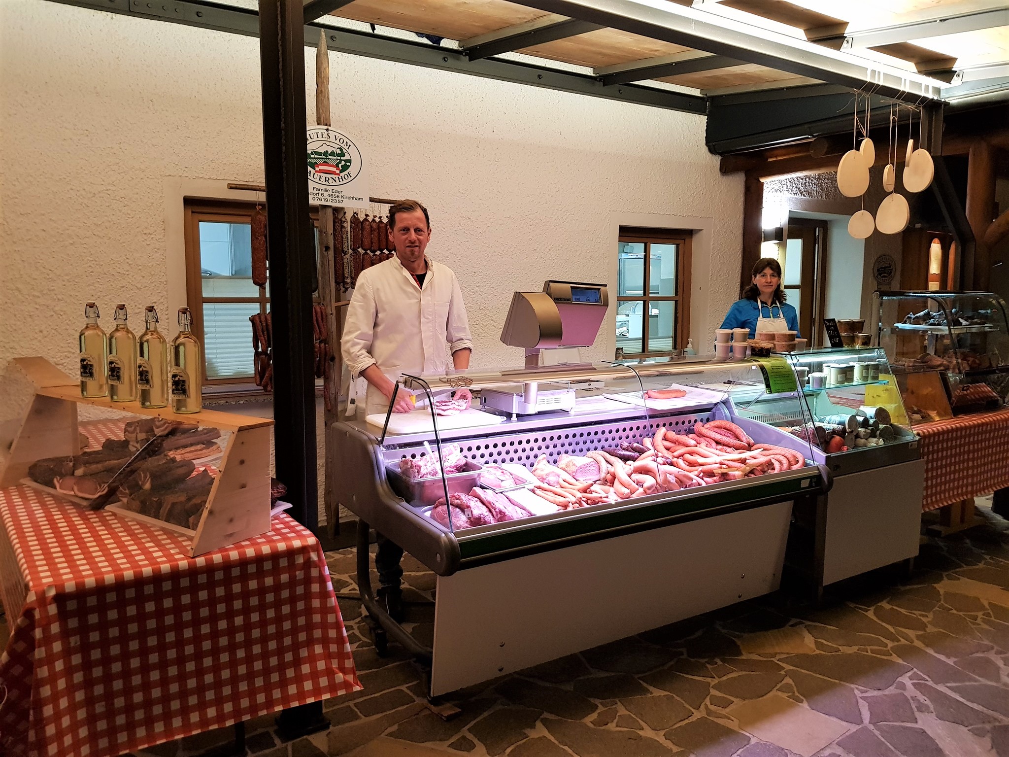 Ein Mann steht hinter der Wursttheke in seinem Hofladen