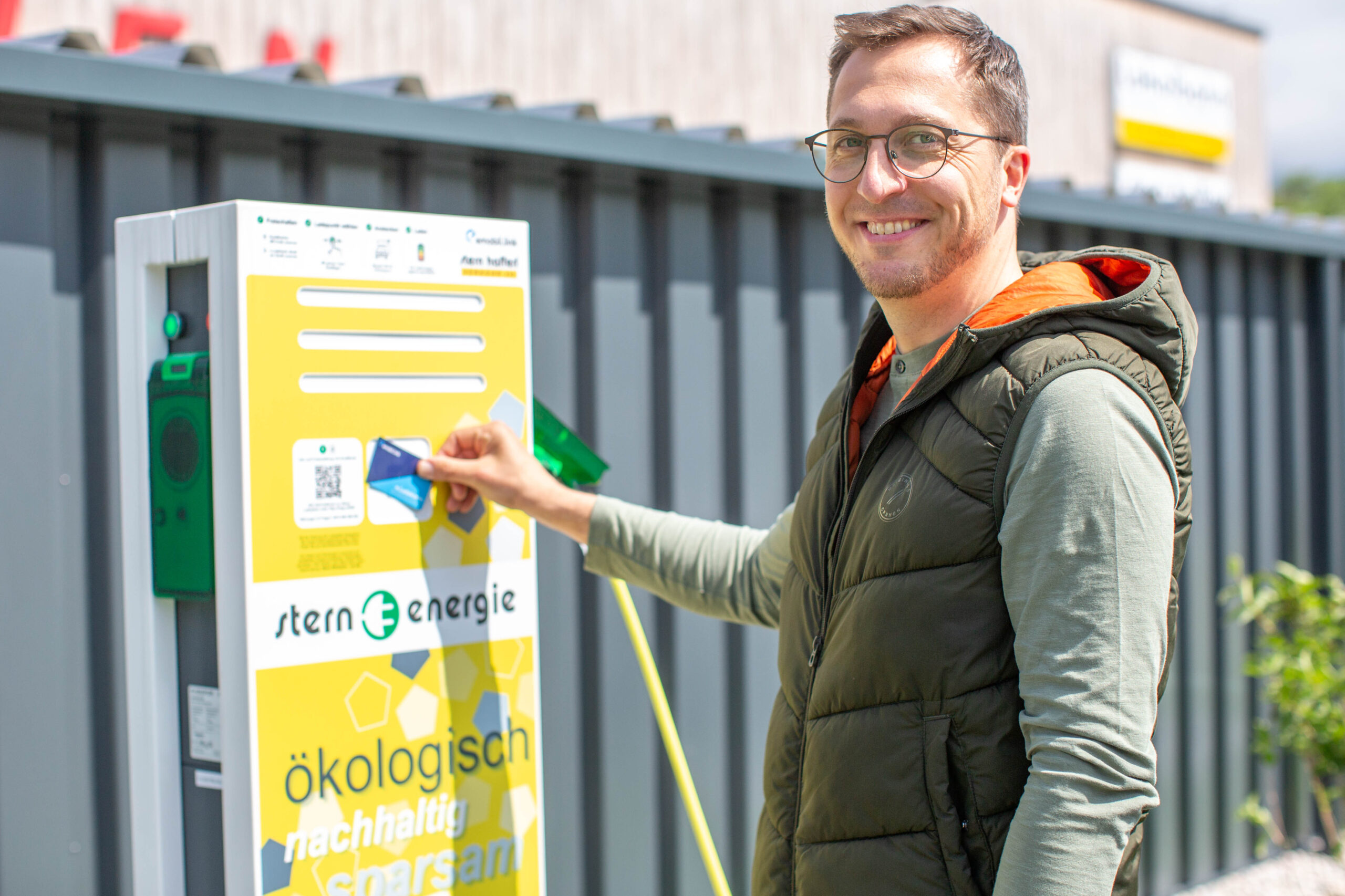 Ein Mann bezahlt bei der Elektroladestation mit der Karte