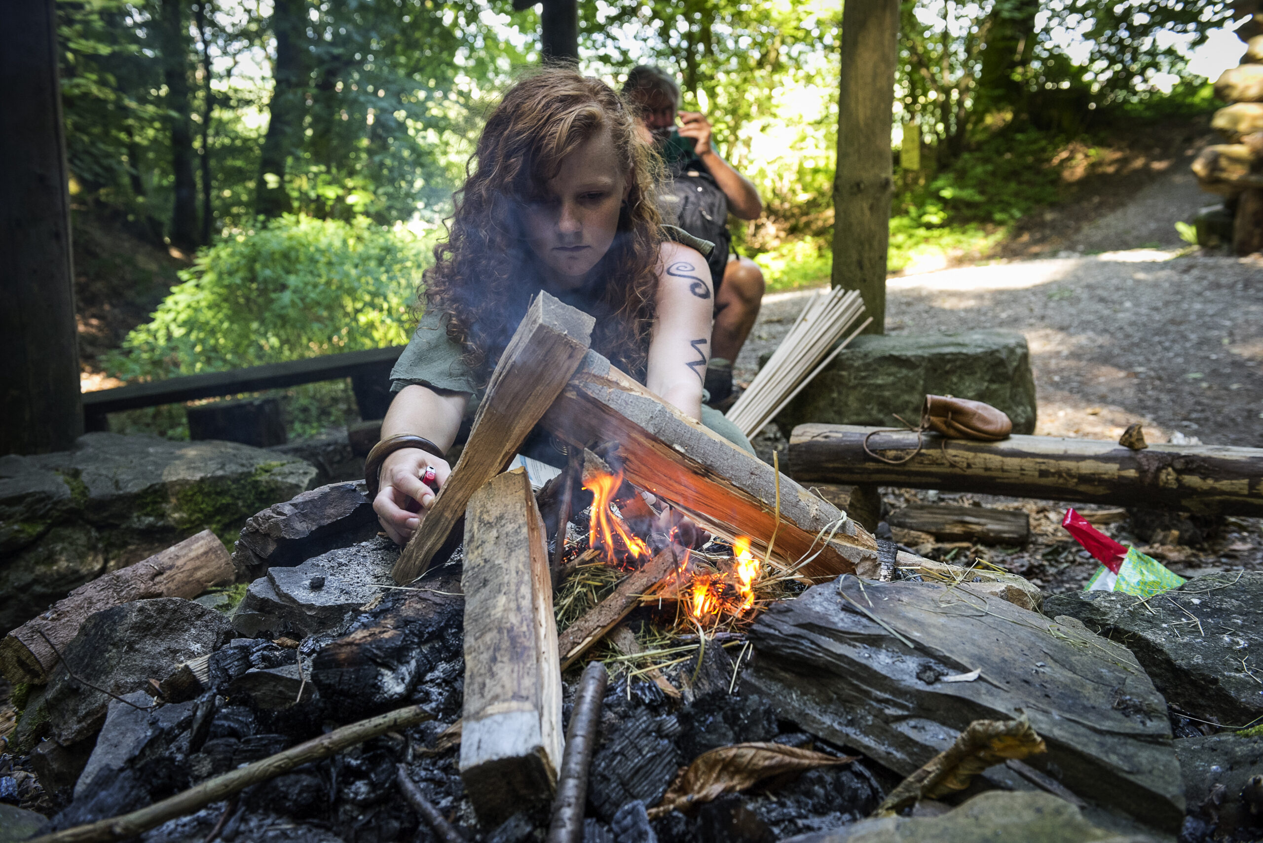 junge Frau zündet Lagerfeuer für das Stockbrot an