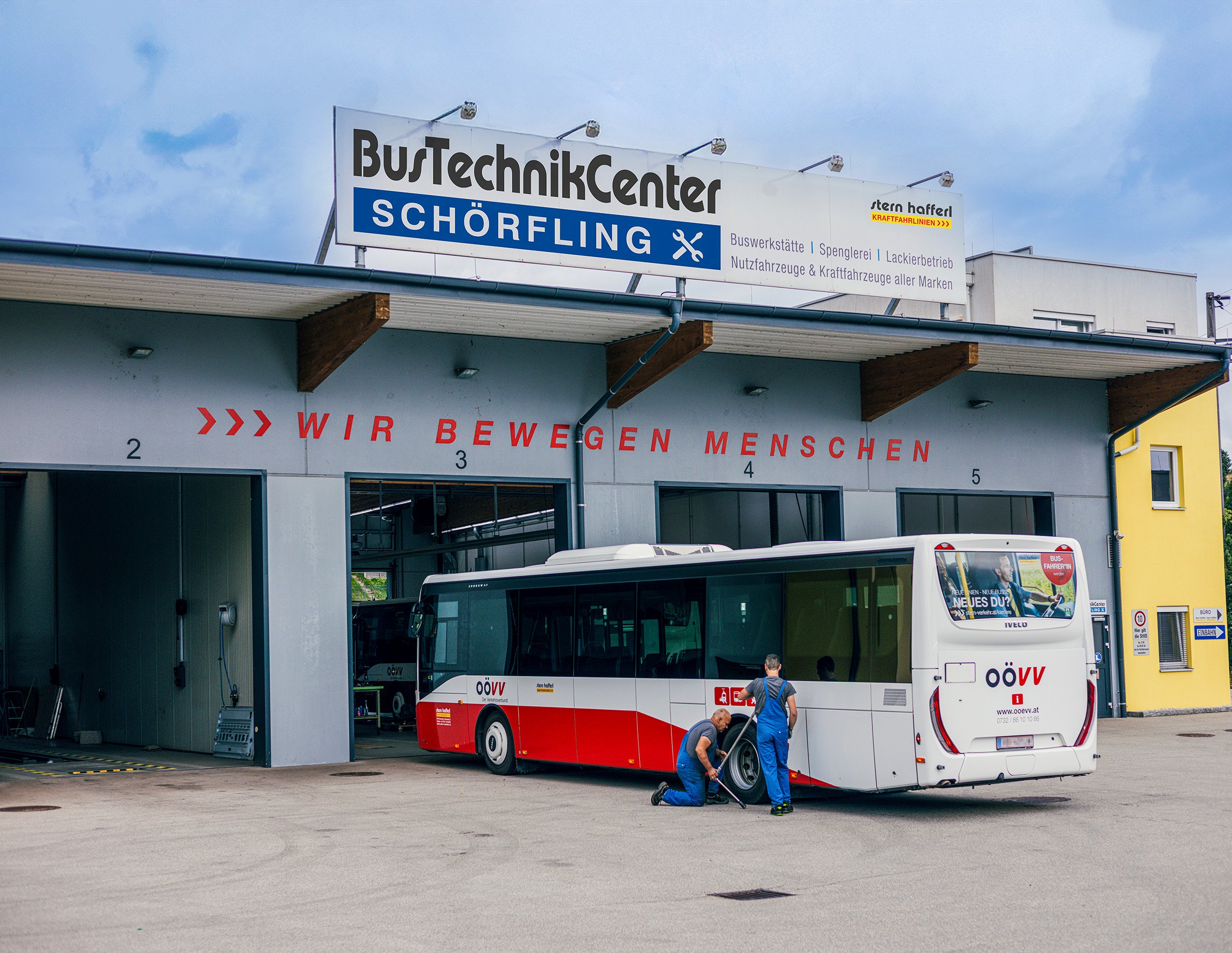 BusTechnikCenter Schörfling von Außen, Tore offen, Bus steht dort und 2 Arbeiter arbeiten
