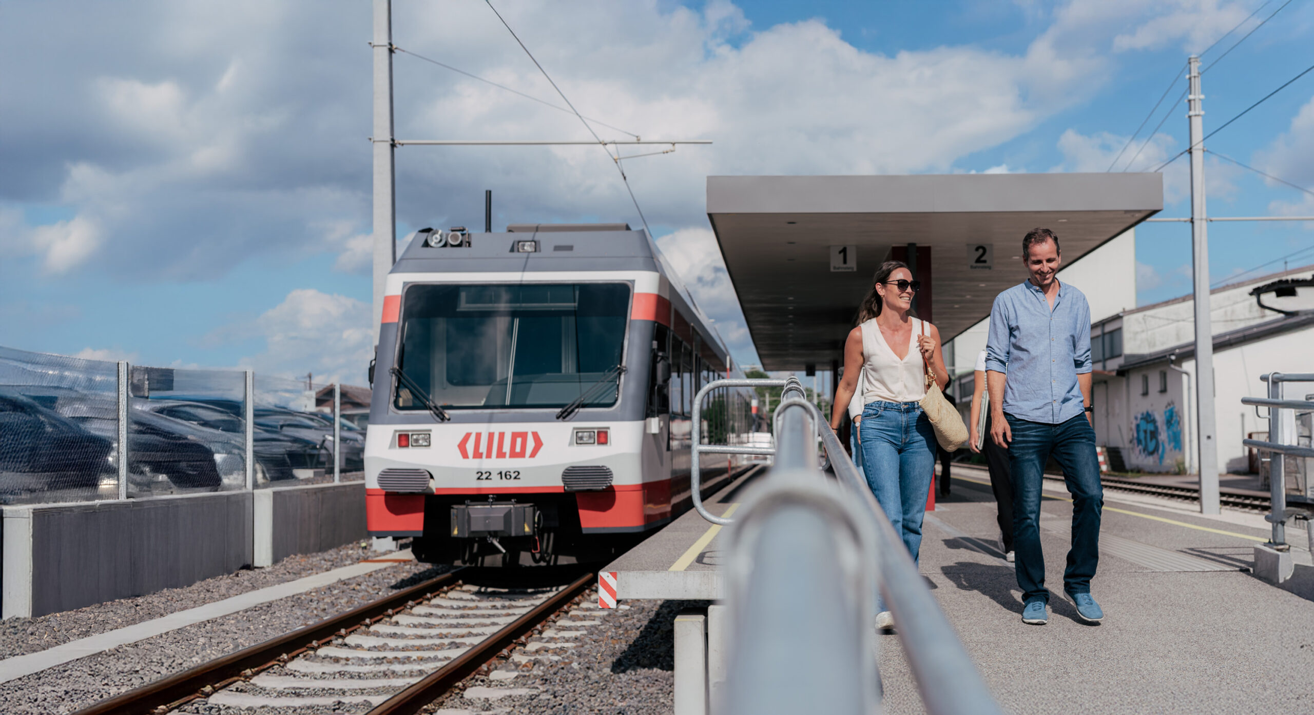 Linzer Lokalbahn auf der linken Seite und am Bahnsteig sind Personen, die aussteigen
